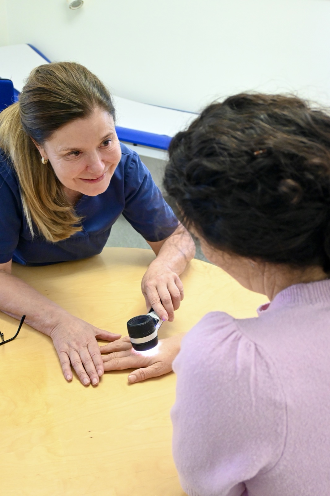 Dr. Triendl untersucht die Hand einer Patientin mit dem Dermatoskop